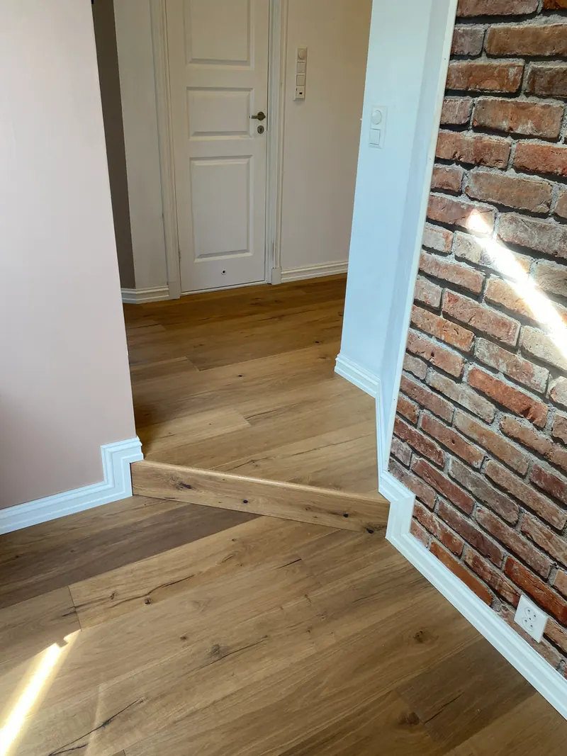 Tregulv og terskel med gulvlister ved en teglvegg